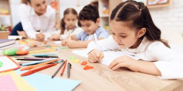 Children write in notebooks with a pen.