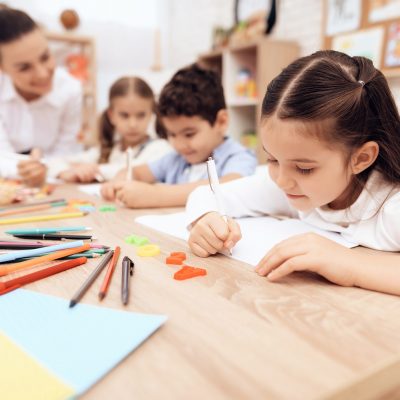 Children write in notebooks with a pen.